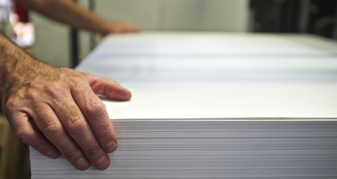 Printer sheet size stack of paper with hand on top